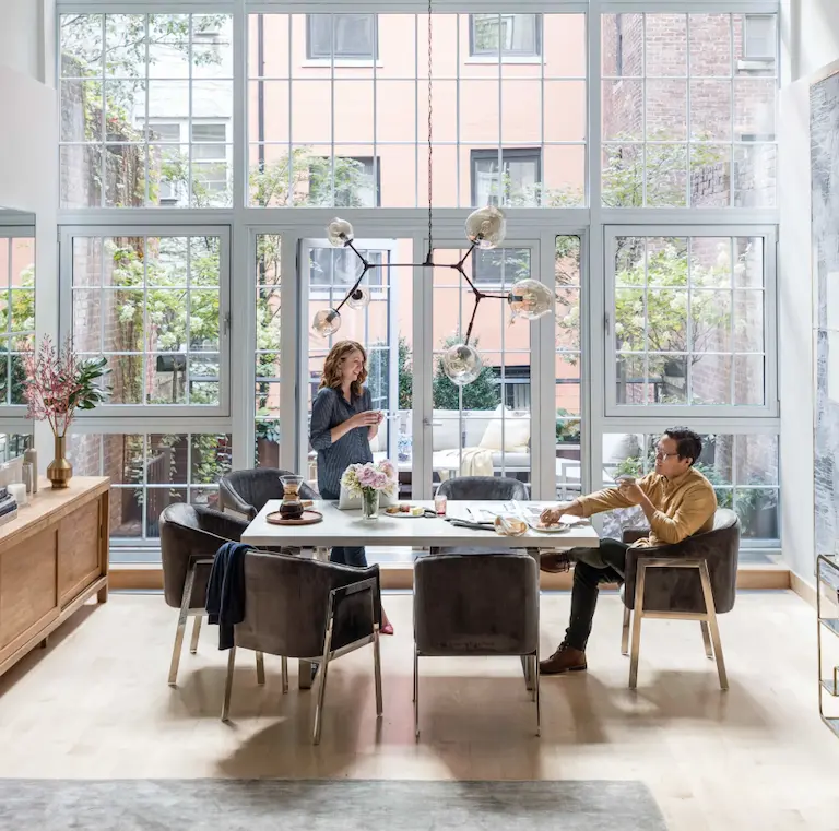 Silicon Valley property real estate agents Couple talking at table with glass wall backdrop.