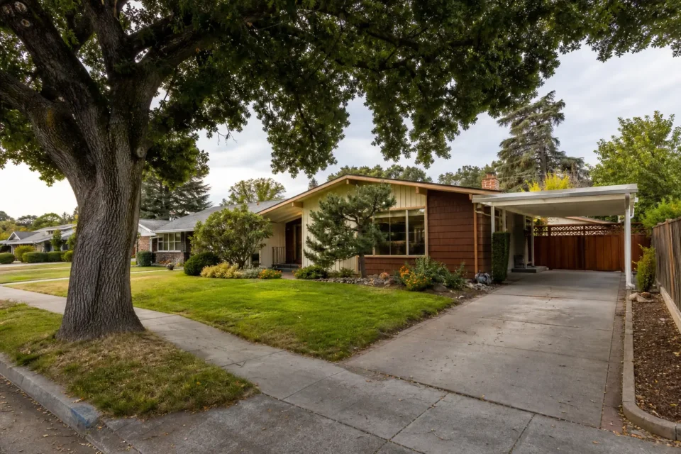Older single-story home with a large front yard, mature tree, and driveway
